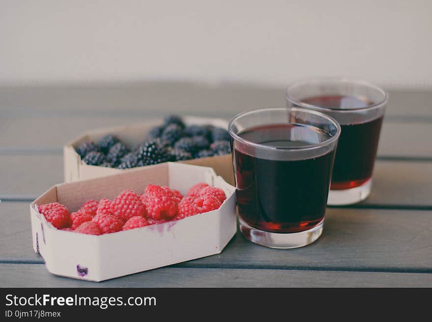 Two Drinking Glasses Filled With Raspberry and Blueberry Fruit Juices