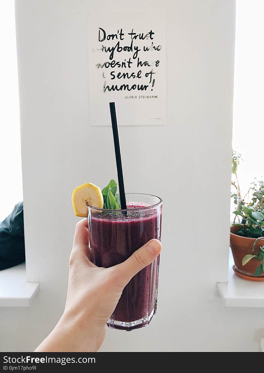 Person Holding Clear Drinking Glass With Purple Smoothie With Quotation Decor