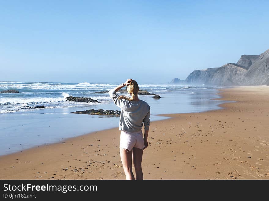 Woman in Gray Long-sleeved Shirt With Pink Short Shorts Standing Near Sea