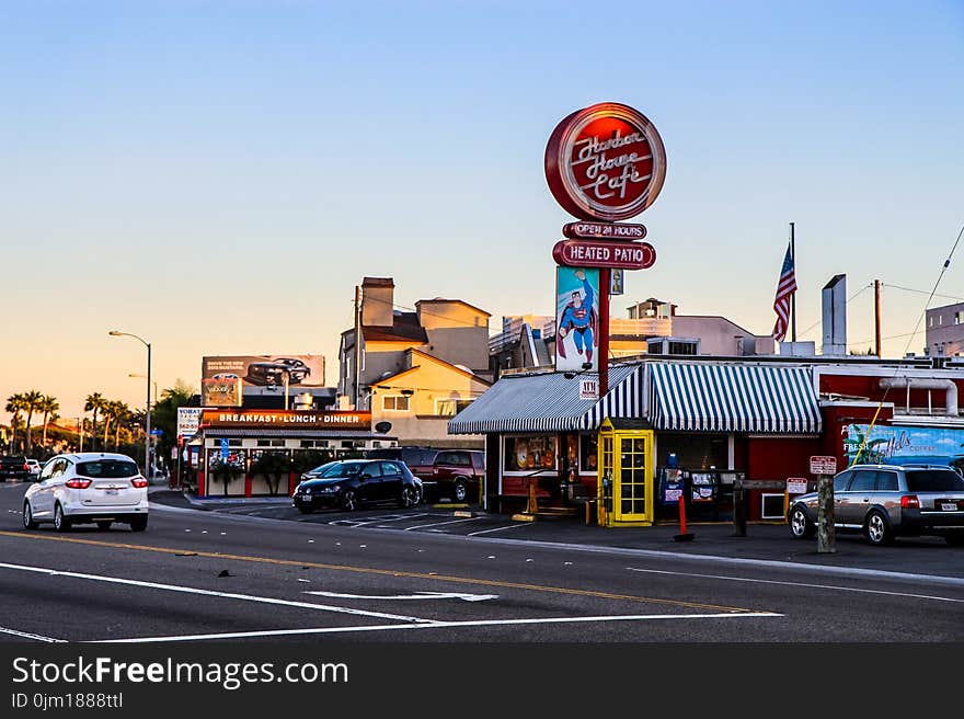 Cafe Signage Near Yellow Telephone Booth and Black Car