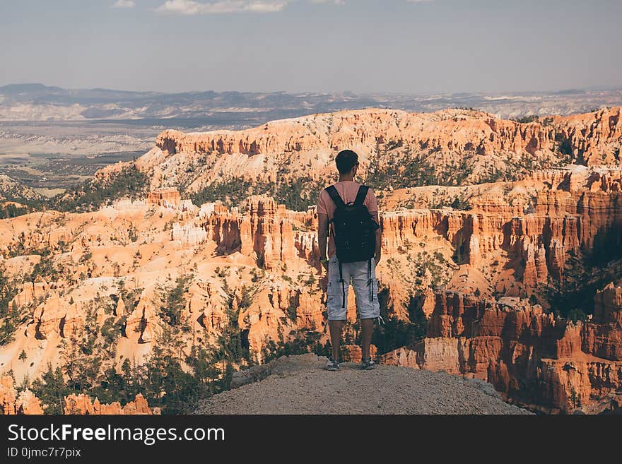 Young man standing by the scenic view of stunning red sandstone hoodoos