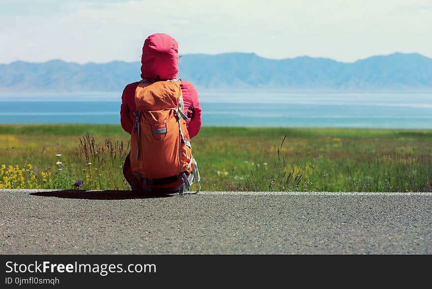 Backpacker sit on the roadside of country road