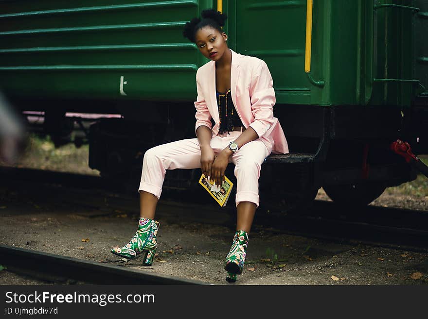 Woman in Pink Blazer Sitting on Green Train