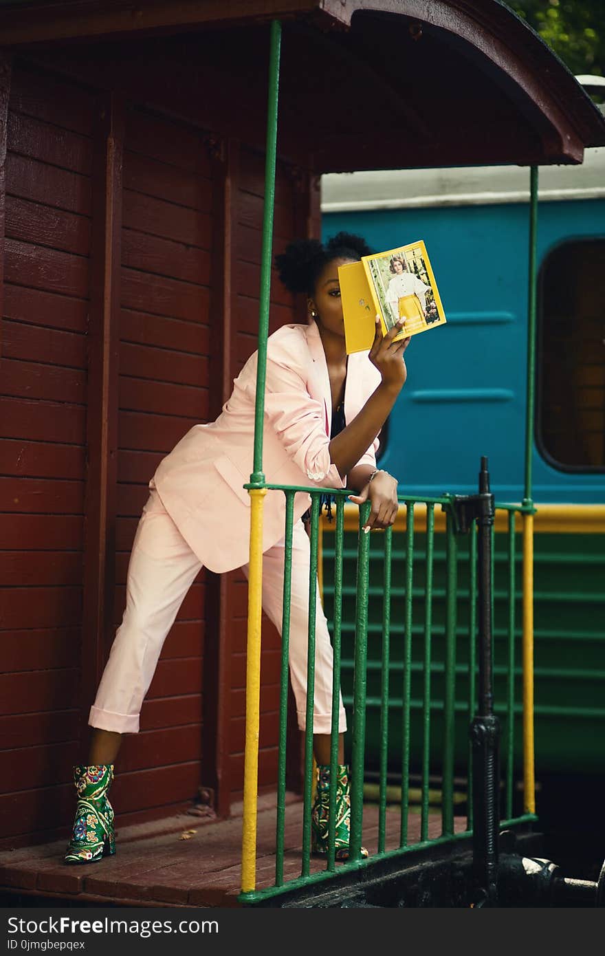 Woman in Pink Suit Coat Leaning on Green Steel Fence