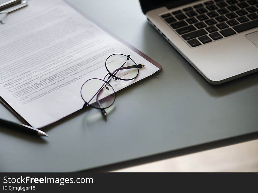 Eyeglasses With Black Frame Beside Macbook Pro