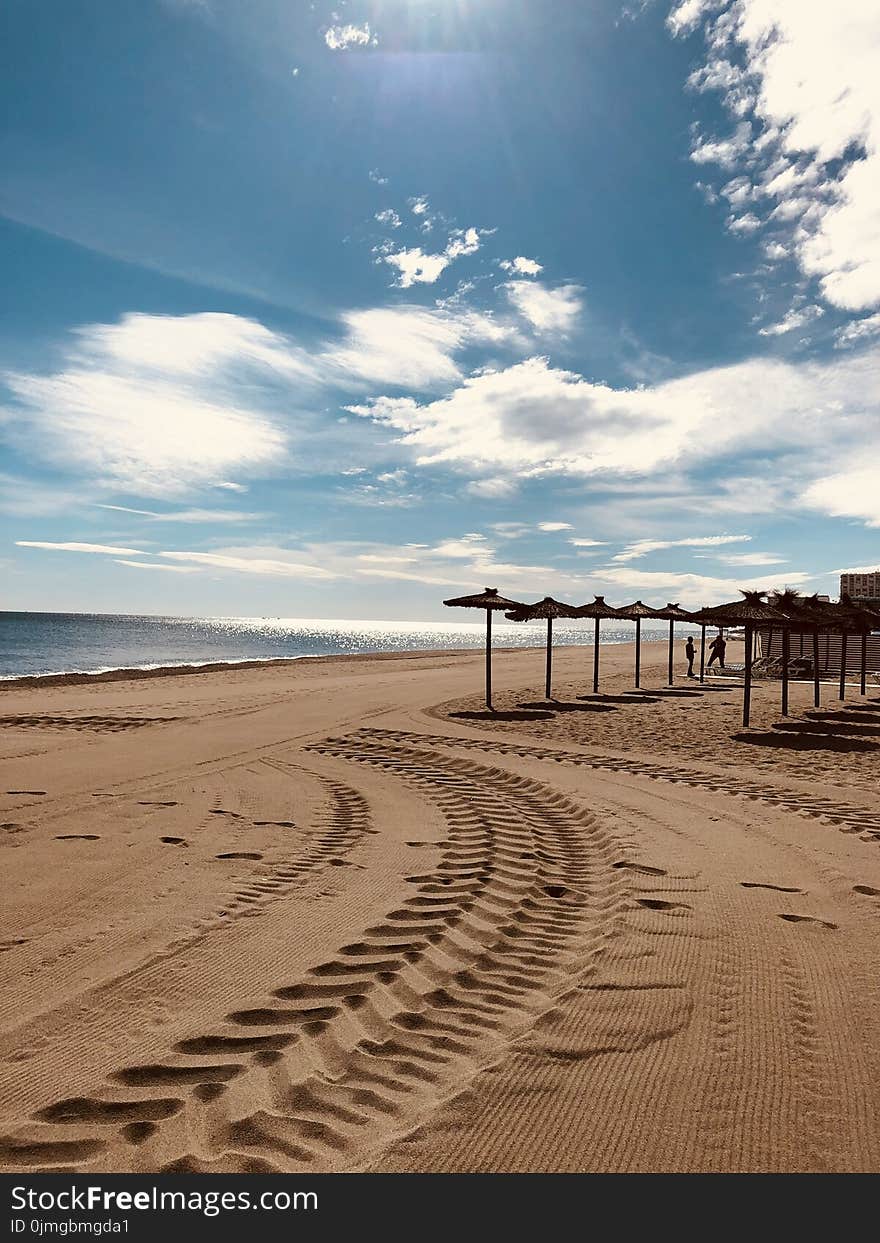 Brown Sand Near Seashore Under Cloudy Sky