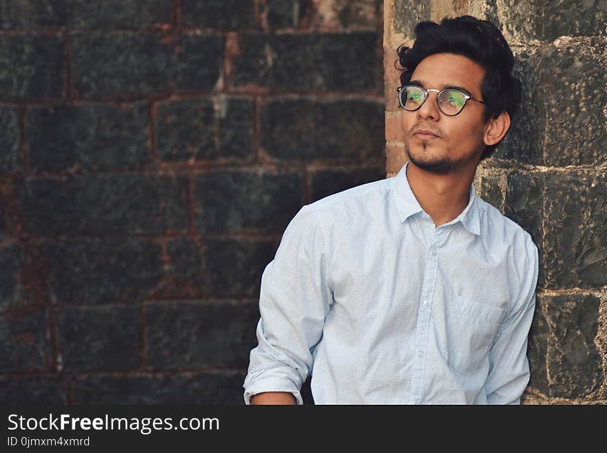 Man Leaning on Black Brick Wall