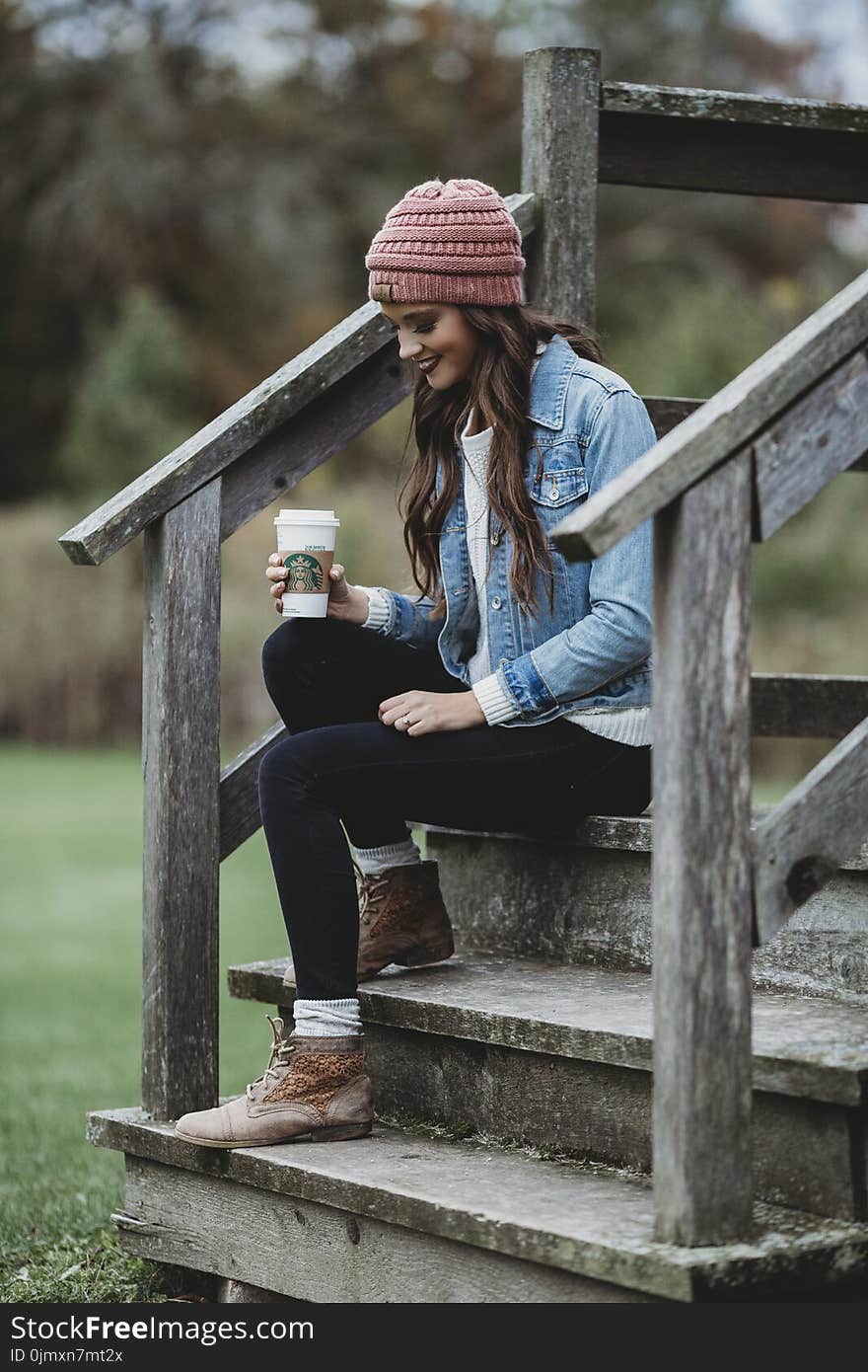 Woman Wearing a Blue Denim Jacket Holding a Cup of Coffee