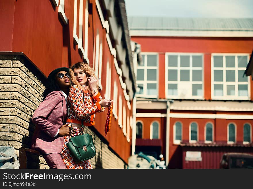 Selective Focus Photographed of Woman Wearing Orange and White Floral Dress and Man Wearing Maroon Suit