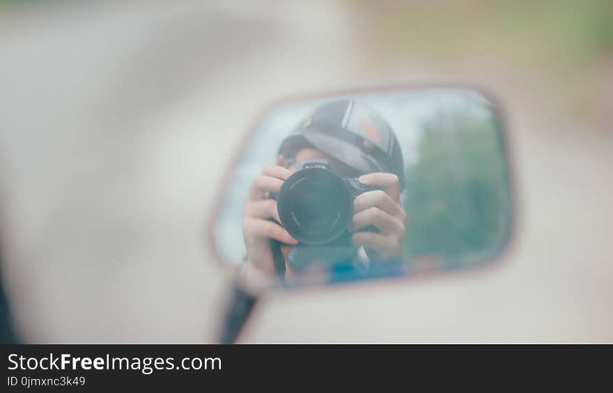 Shallow Focus Photography of Person Holding Dslr Camera in Mirror Reflection