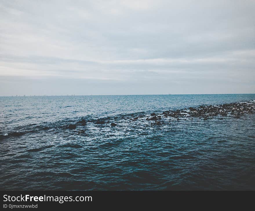 Photography of Ocean Under Cloudy Sky