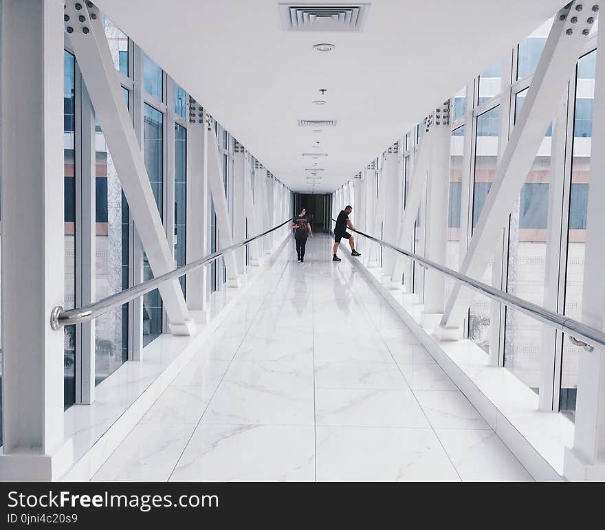 Two People Standing on Hallway Near Glass Window