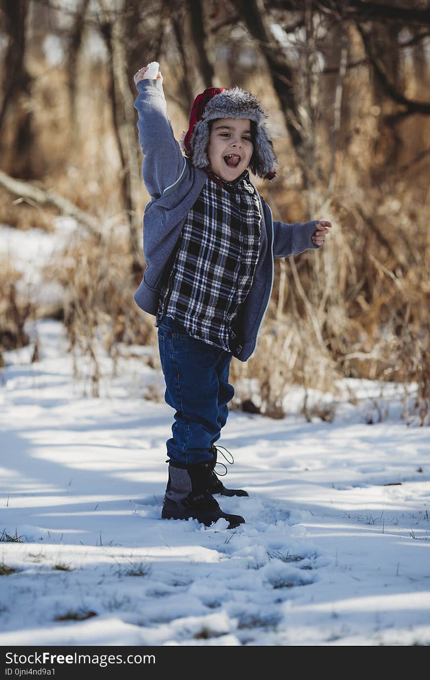 Boy in Gray Jacket and Blue Jeans Standing on Snow Outdoor