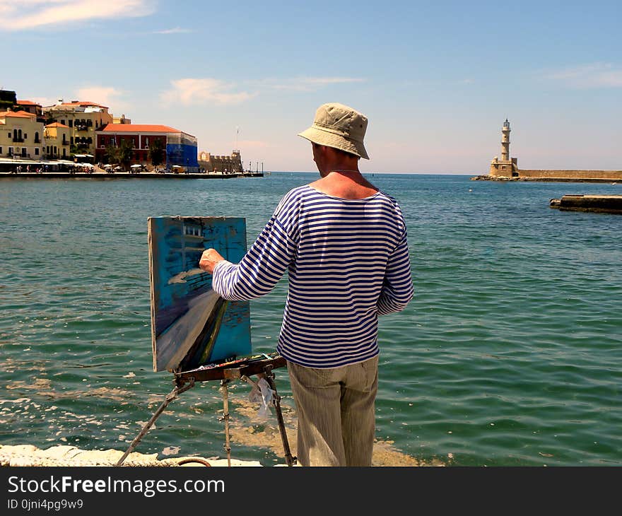 Man in White and Blue Striped Long-sleeved Shirt Painting Near Seashore