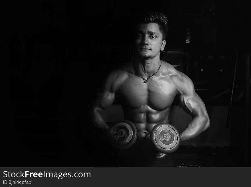 Grayscale Photo of a Man Holding Pair of Dumbbells