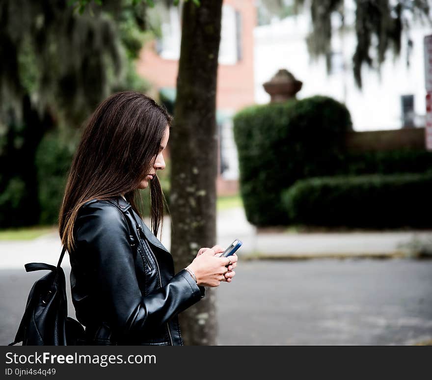 Woman in Black Leather Jacket Holding Smartphone