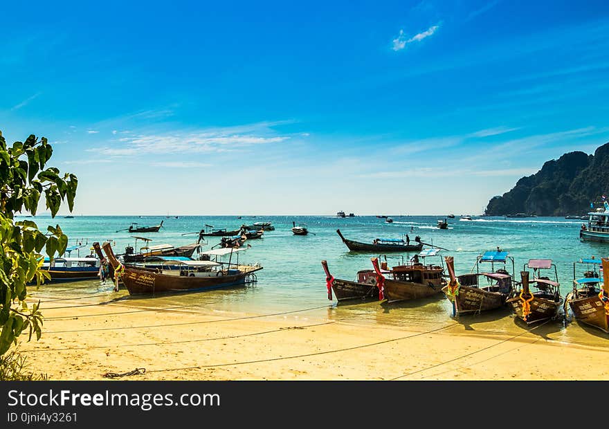 Several Canoes in Shoreline Near Bodies of Water Landscape Photograph