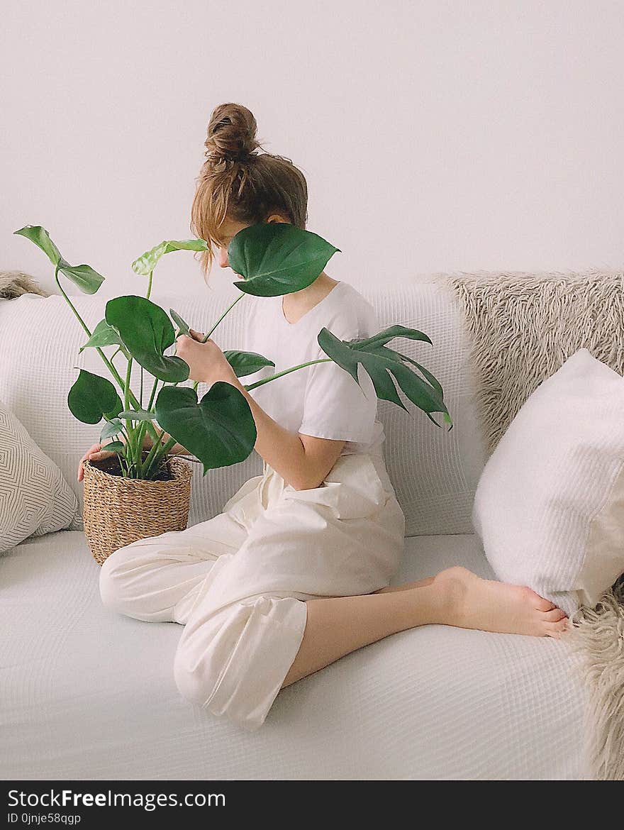 Woman Wearing White Crew-neck Shirt and White Pants While Sitting on White Couch