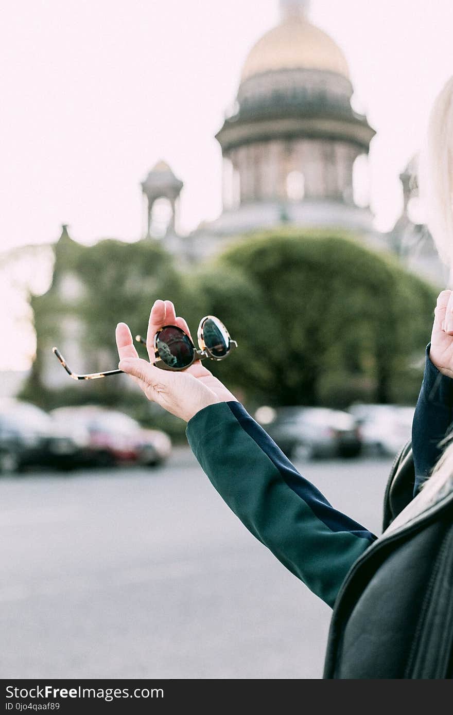 Selective Focus Photography of Person Holding Black Round Sunglasses