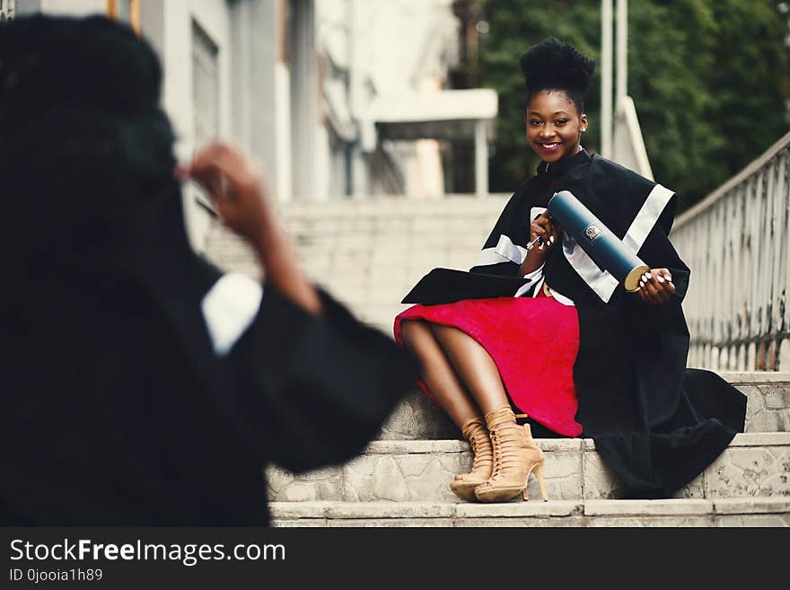 Woman Wearing Black Graduation Coat Sits on Stairs