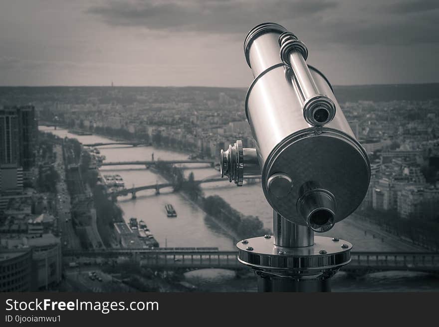 Grayscale Photography of Observation Telescope Overlooking City Riverbank