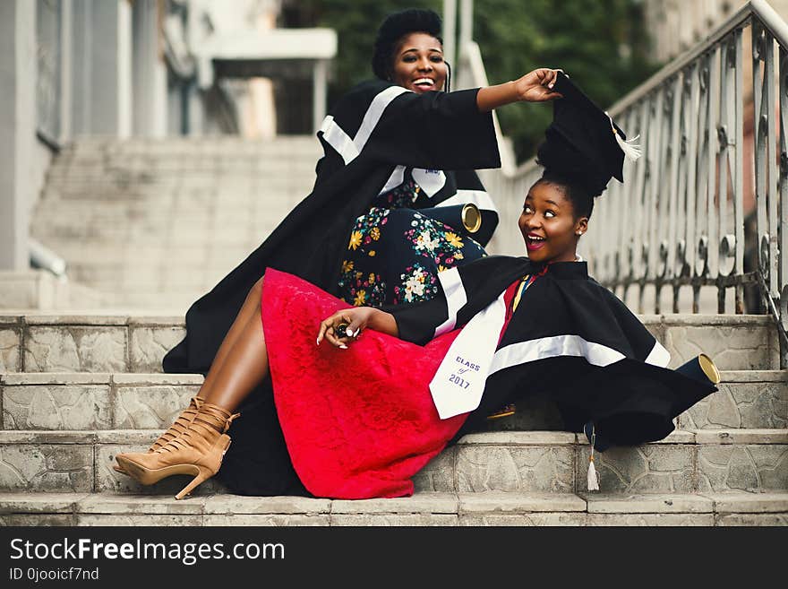 Shallow Focus Photography of Two Women in Academic Dress on Flight of Stairs