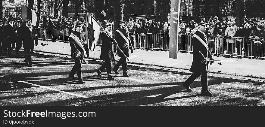 Men Walking on Streets Carrying Flag during Parade In Grayscale Photo