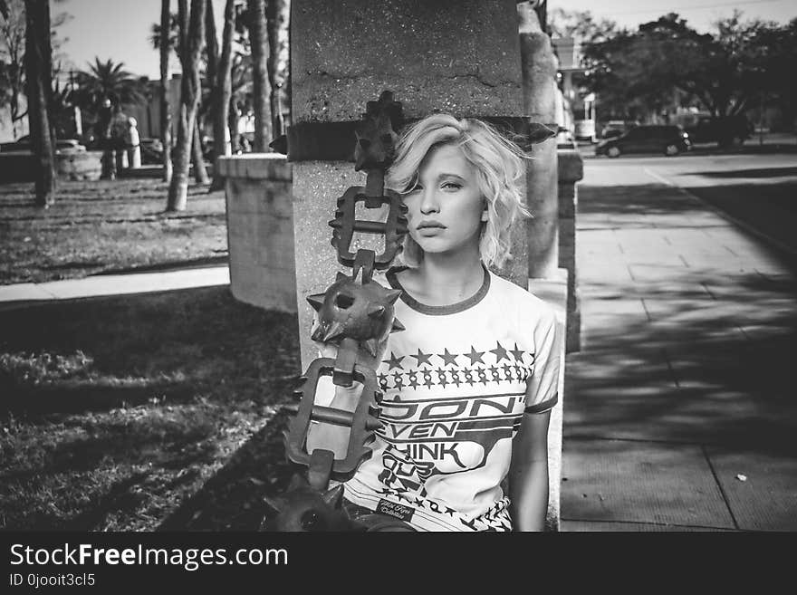 Female Leaning on Gray Concrete Post Grayscale Photo