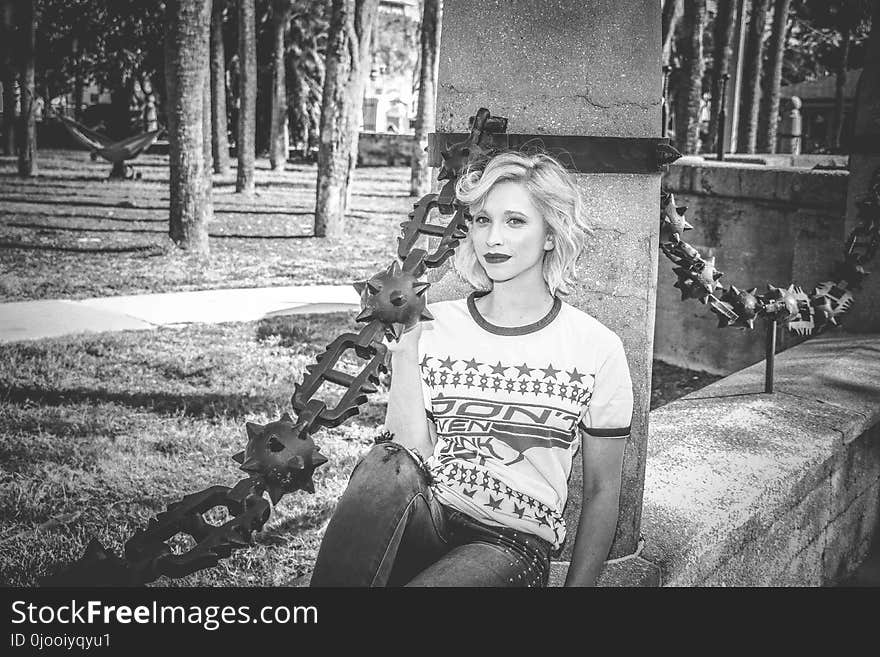 Grayscale Photo of Woman Sitting on Concrete Wall