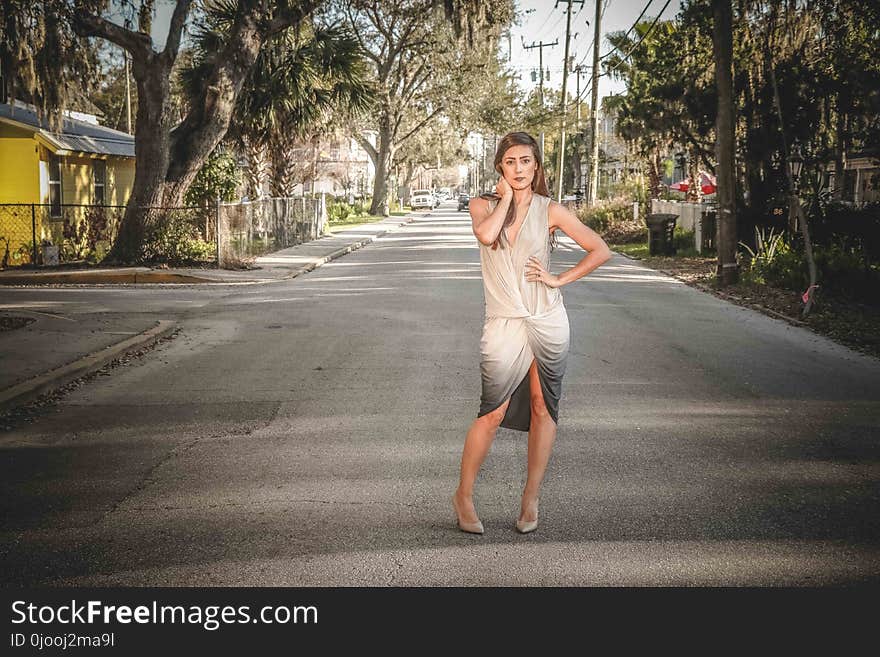 Woman Wearing Grey and Beige Dress Standing on Center of Street