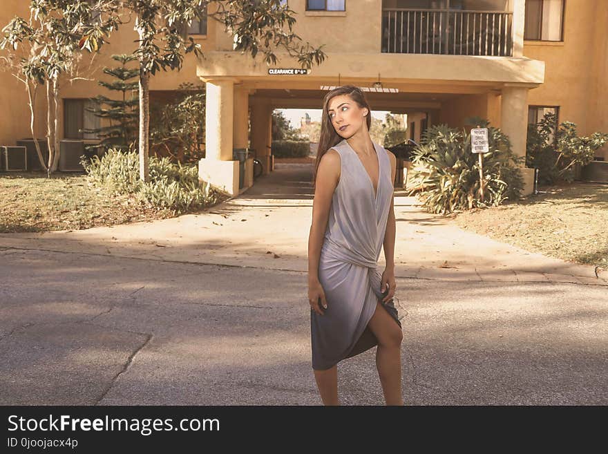 Woman in Gray Deep V-neck Sleeveless Tulip Dress Standing on Gray Floor