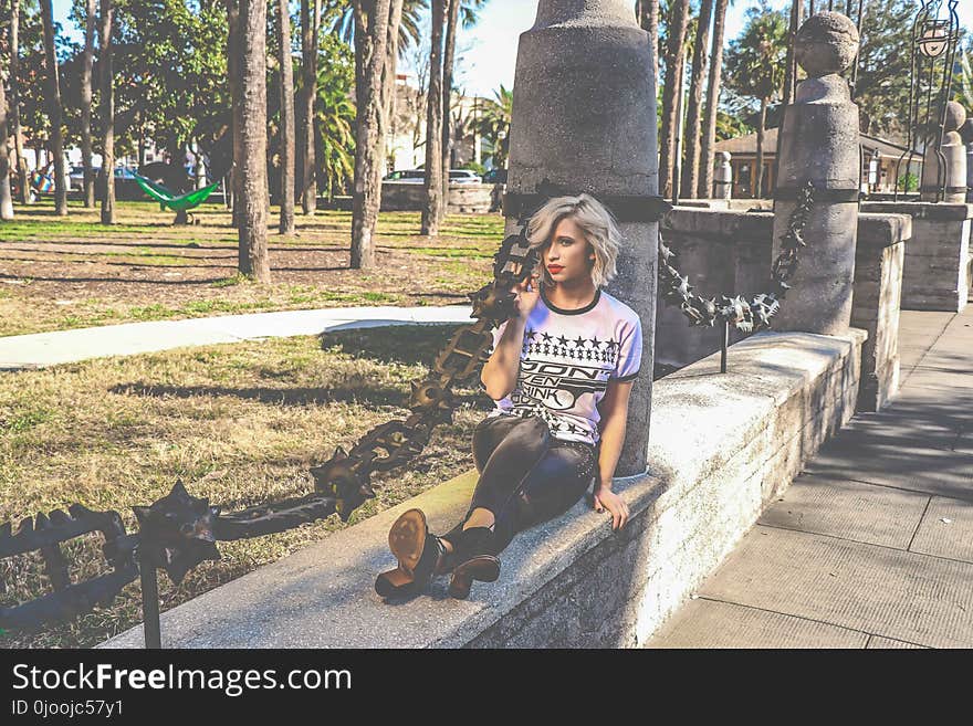 Woman in White and Black T-shirt and Pants Sitting on Beam