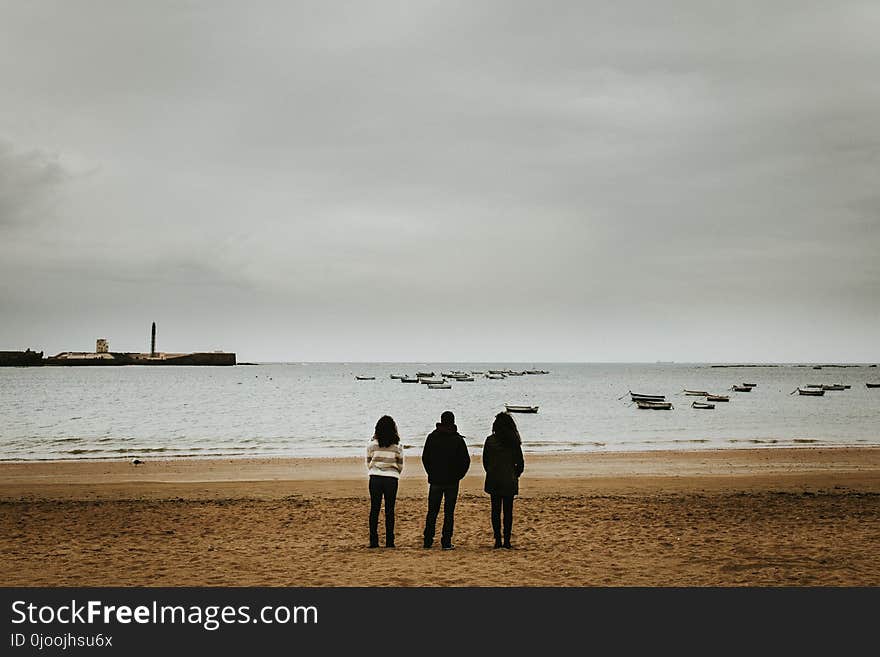 Three Person Standing Near the Seashore