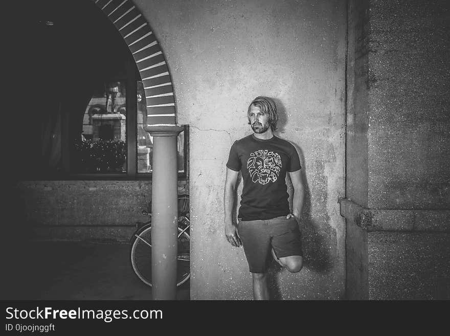 Man in Crew-neck T-shirt and Shorts Leaning on Wall