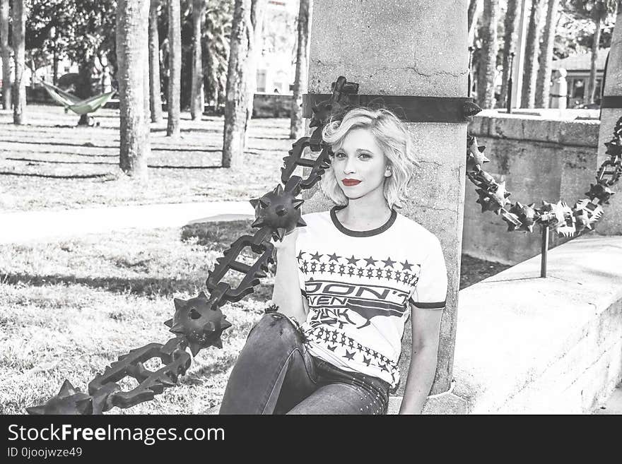 Grayscale Picture of Woman Sitting on Black Post