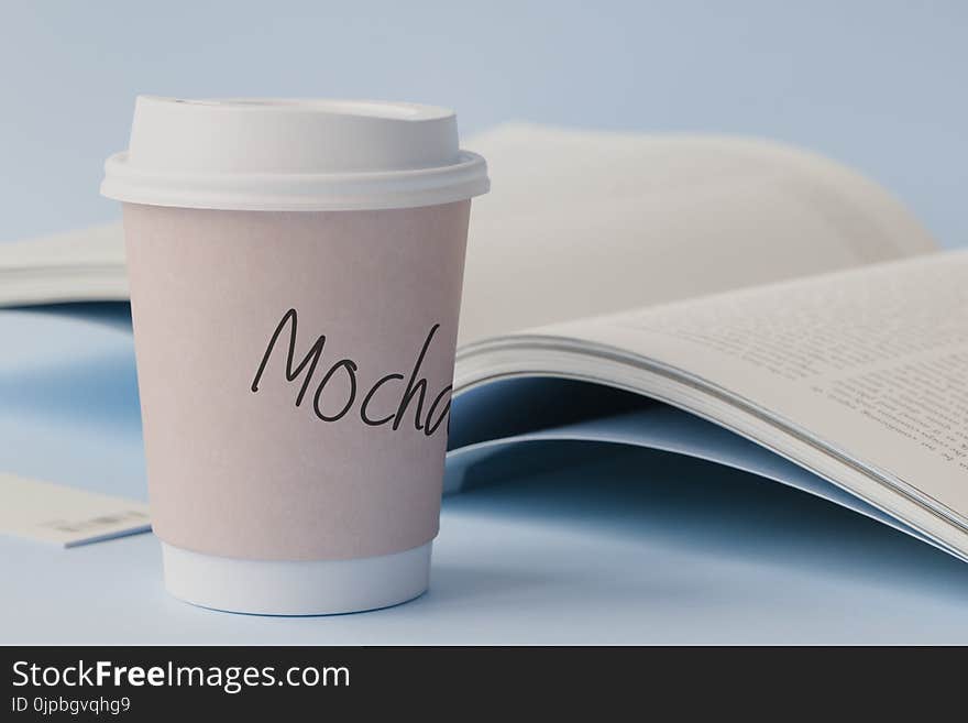 Mocha Labeled White Disposable Coffee Cup Beside Book