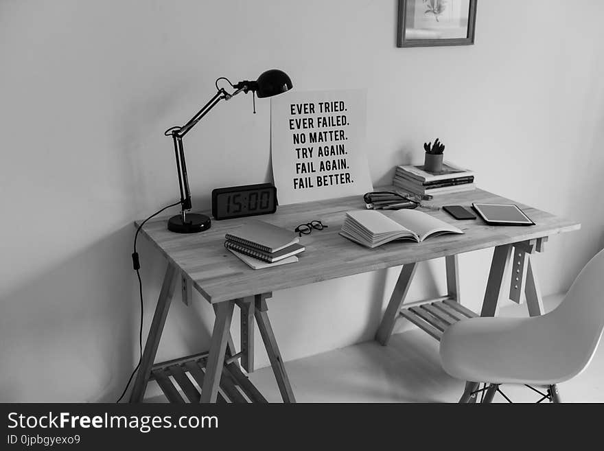 Grayscale Photography of Desk With Books and Table Lamp