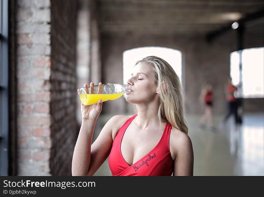 Selective Focus Photography of Woman in Red Tank Top Drinking