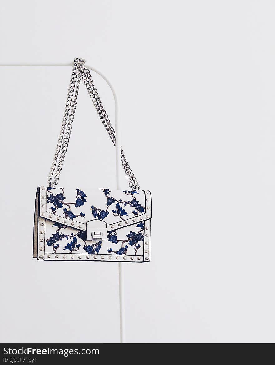 White and Blue Floral Flap Sling Bag Hanging on White Steel Rack