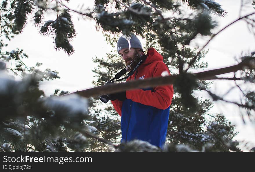 Man in Red and Blue Jacket Near Trees