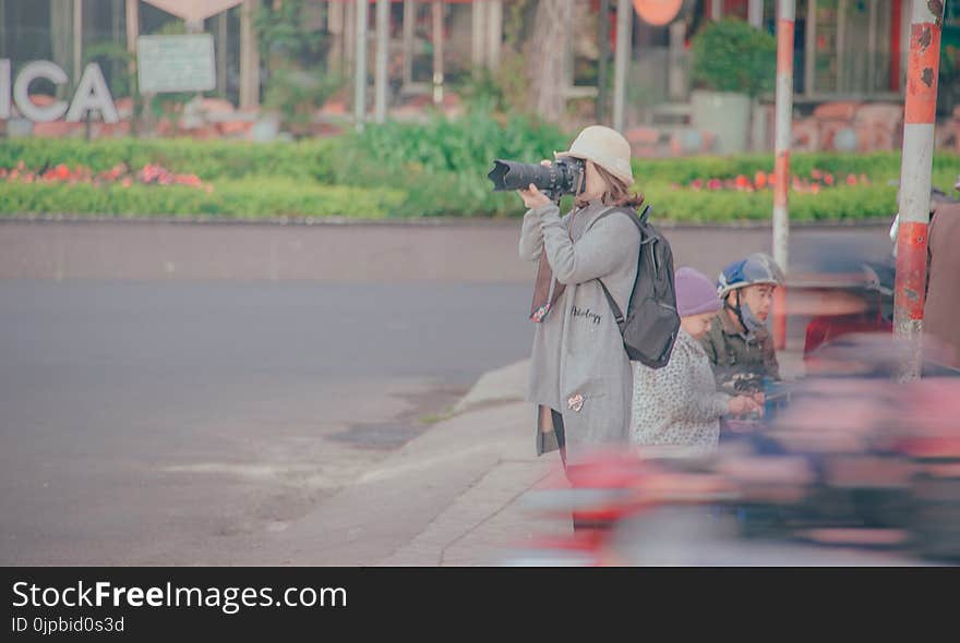 Woman Holding Black Dslr Camera Taking Picture