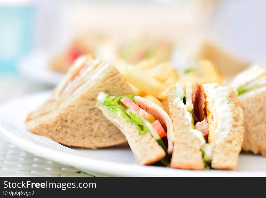 Selective Focus Photography of Plate of Sliced Clubhouse Sandwich