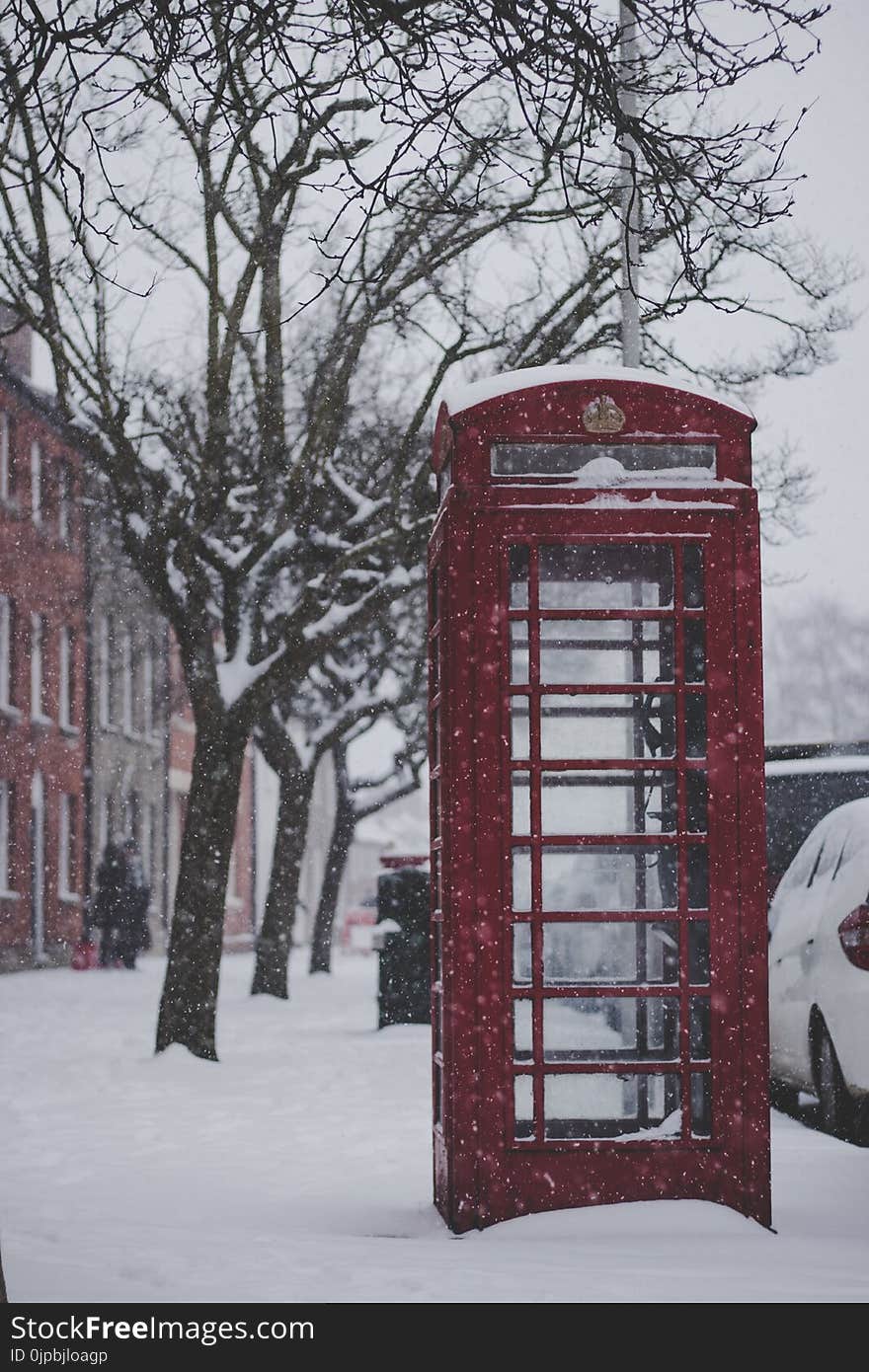 Red Telephone Booth on the Sidewalk With Snow