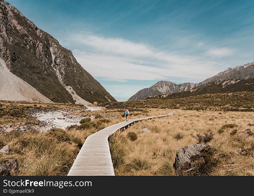 Photo of a Man Walking on Boardwalk