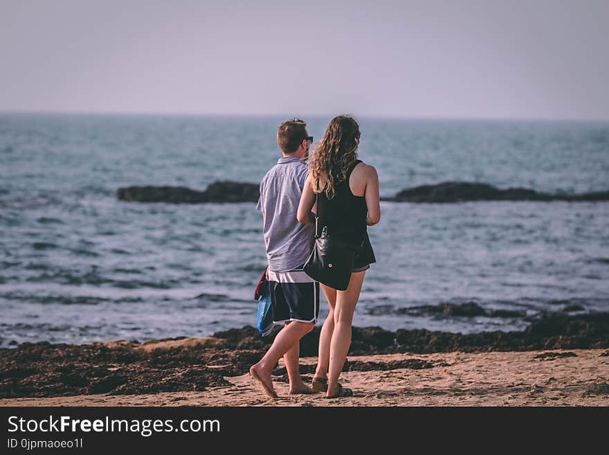 Woman and Man Walking Near Seashore