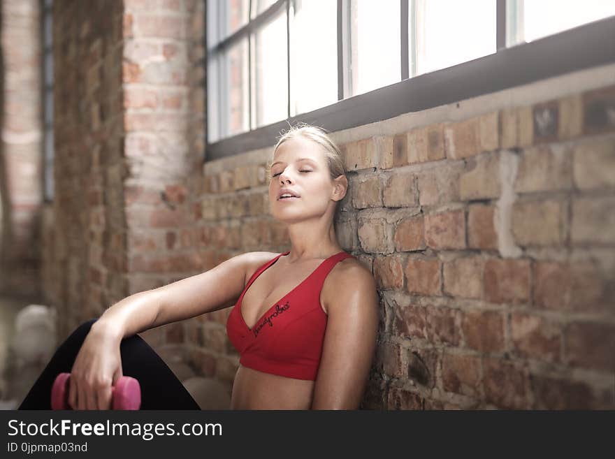 Woman in Red Brassier Leaning on Brown Brick Wall