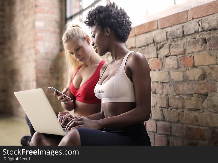 Two Woman Wearing Red and White Sports Bras