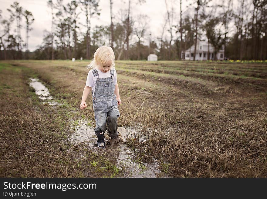 Toddler Wearing Blue Denim Overall Pants Walking on Wet Withered Grass