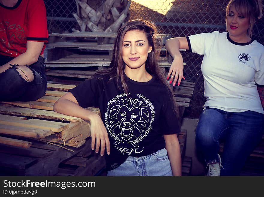 Woman Leaning on Brown Wooden Board Beside Woman Wearing White Crew-neck Shirt