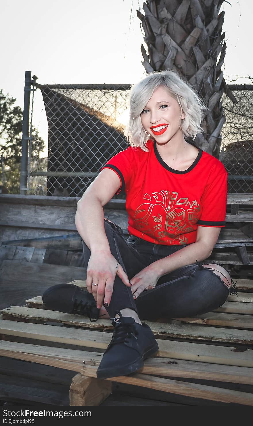 Woman Sit on Pallet Wearing Crew-neck T-shirt and Distressed Black Fitted Jeans